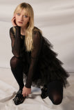 Model posing in a black solid mesh tulle-layered romper, showcasing a chic and elegant silhouette.