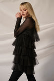 Model wearing a stylish black tulle-layered romper with mesh sleeves, showcasing an elegant babydoll silhouette.