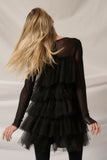 Elegant black tulle-layered romper showcasing a chic back view with flowing hair and ruffled layers. Perfect for special occasions.
